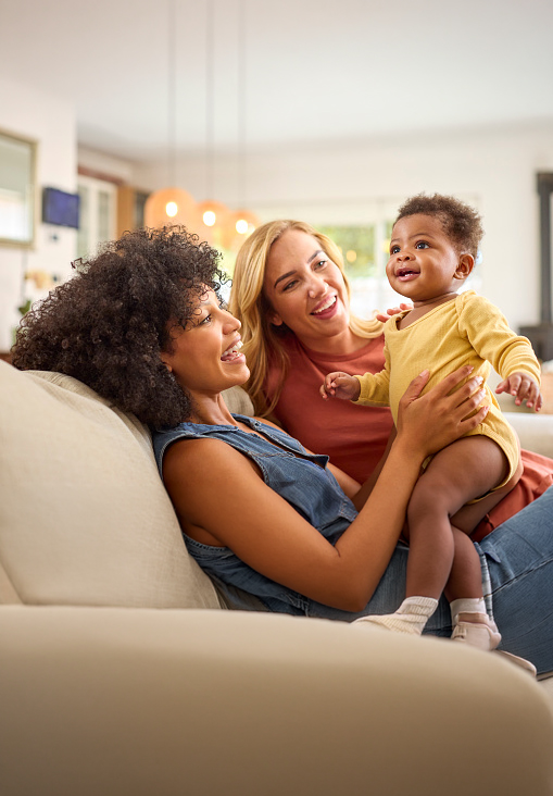 A caucasian woman and a mixed race woman with their mixed race baby